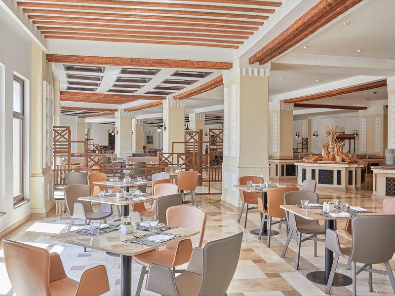 Restaurant moderne et lumineux avec tables en bois et chaises beige à la lumière du jour.