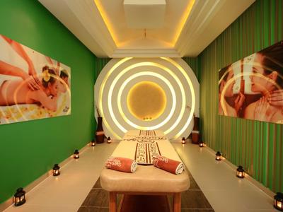 Moderní spa s masážním lehátkem, zelenými zdmi a uklidňujícími kruhovými světly.