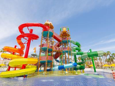 Kleurrijke glijbanen en zwembaden in een waterpark bij heldere lucht.