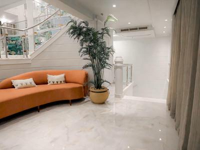 Interno di un hotel moderno con divano arancione e pianta in vaso.