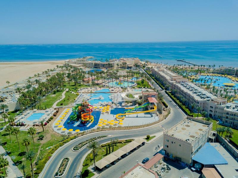 Vista aérea de un resort de playa con piscina, toboganes de agua y mar adyacente.