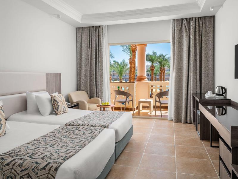 Modern hotelkamer met twee éénpersoonsbedden en balkon met zeezicht.