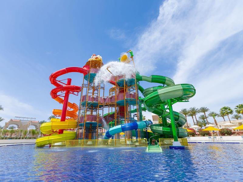 Parc aquatique coloré avec toboggans et piscine sous un ciel bleu dégagé.
