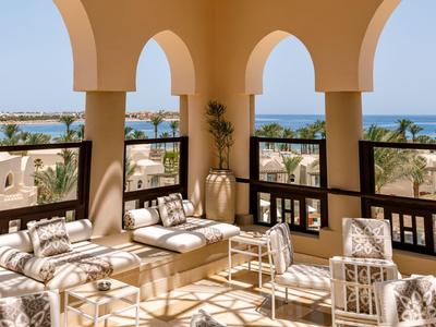Terraza acogedora con sofás bajo arcos con vista al mar azul.