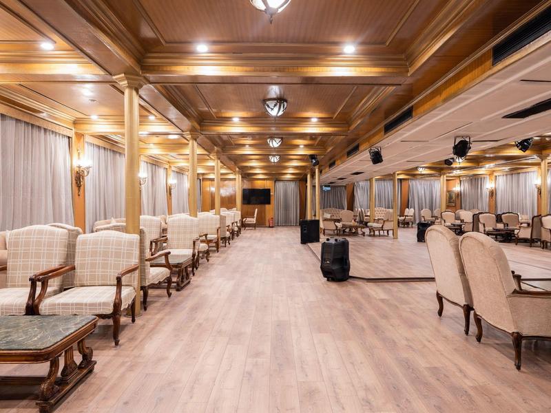 Eleganckie wnętrze z fotelami i stolikami w dużym, jasnym salonie.