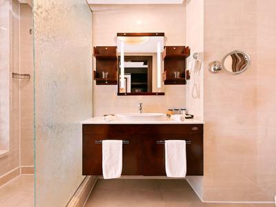 Moderne badkamer met houten wastafelmeubel, dubbele wasbakken en grote spiegel in een hotelkamer.