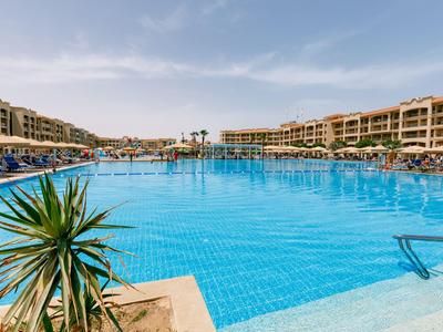 Grand piscine d'hôtel avec chaises longues et bâtiments à plusieurs étages sous un ciel bleu
