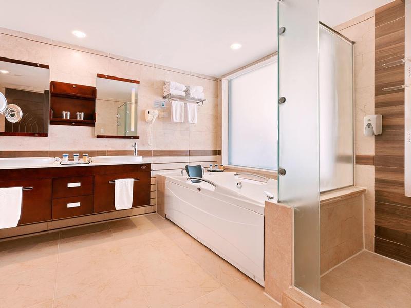 Baño moderno con bañera, tocador grande y decoración en tonos madera y blanco.