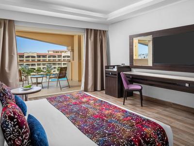 Moderne Hotelzimmer mit Balkon, Schreibtisch, Stuhl und farbenfrohem Teppich.