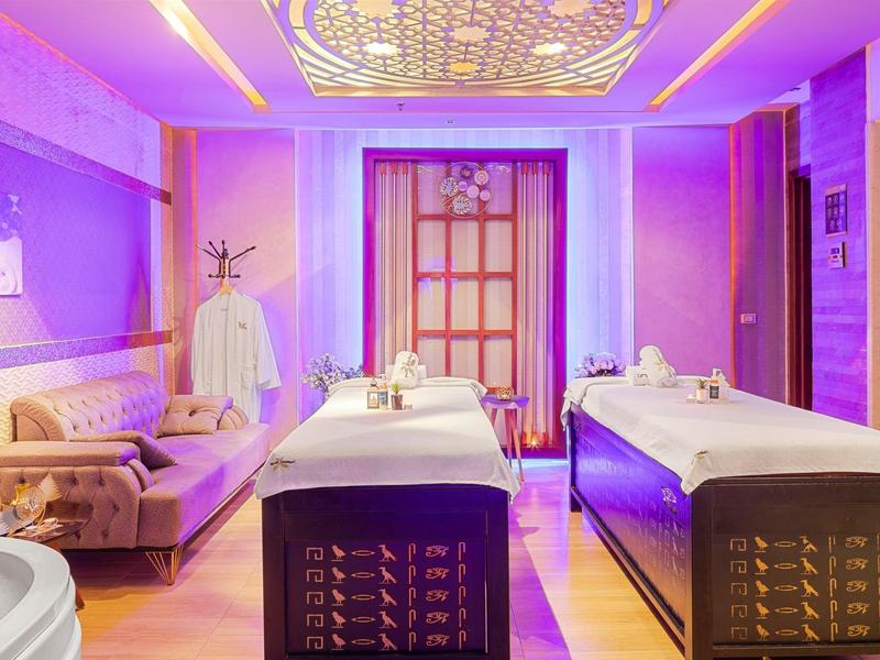 Elegantní spa místnost se dvěma masážními lehátky, fialovým osvětlením a moderním zařízením.