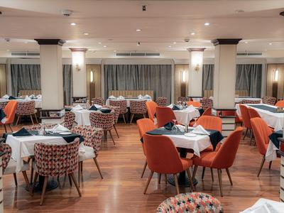 Ristorante elegante con tavoli, sedie arancioni e pavimento in legno.