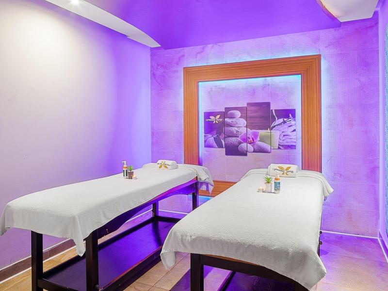 Spa room with two massage tables, soft lighting, and a calming purple and blue ambiance.
