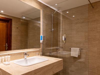 Moderne badkamer met grote wandspiegel, wastafel en glazen douchecabine.