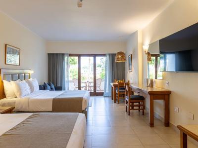 Spacious hotel room with two beds, balcony, desk, TV, and modern decor.