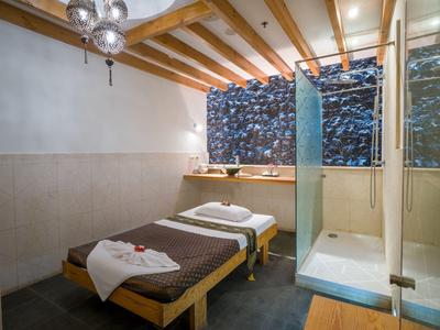 Camera d'hotel con letti singoli, travi a vista in legno e bagno moderno con parete di vetro.