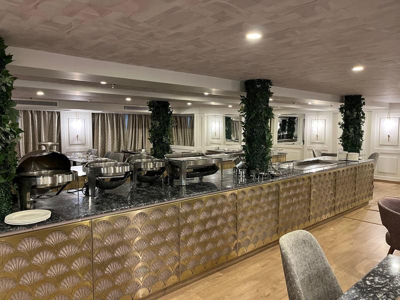 Buffet elegante con piano in granito nero e colonne decorate con piante verdi.