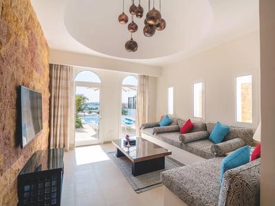 Sala moderna con sofá gris, cojines coloridos y vista a la terraza y al mar.