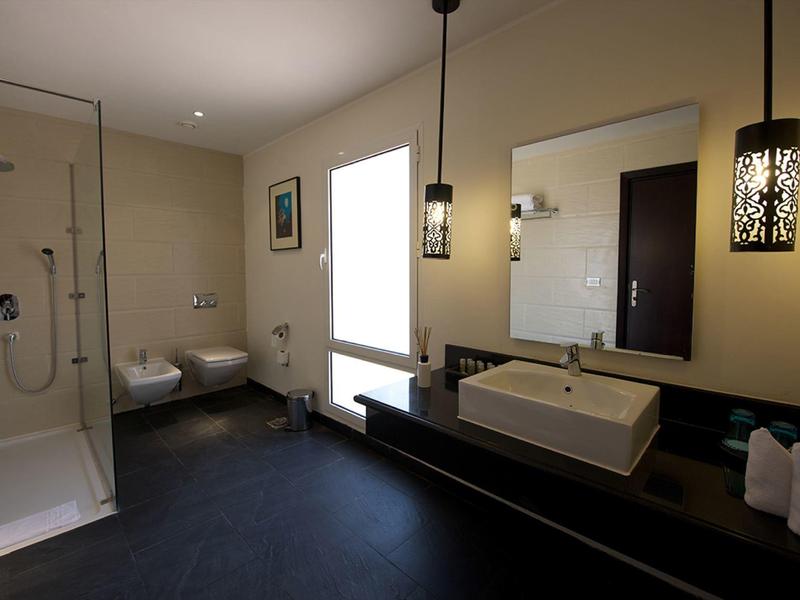 Baño moderno con ducha, lavabo, inodoro y bidé en una habitación de hotel.