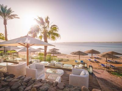 Resort sulla spiaggia con sdraio, ombrelloni e palme all'alba sul mare.