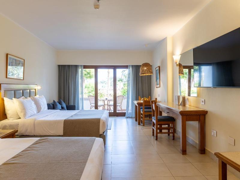 Chambre d'hôtel moderne avec deux lits, télévision murale et balcon lumineux.