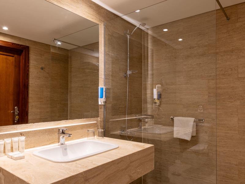 Moderne badkamer met grote wandspiegel, wastafel en glazen douchecabine.