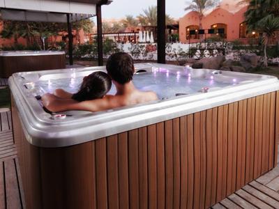 Couple relaxing in an outdoor hot tub in a hotel garden.