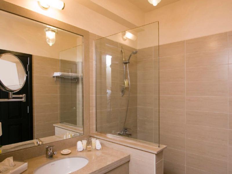 Moderne badkamer met beige betegelde douche en wastafel met grote spiegel.