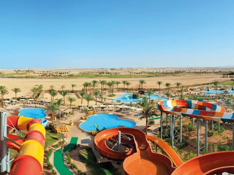 Colorful water slides in a large tropical water park with palm trees and blue pools.