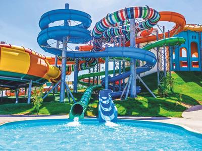 Kolorowy park zjeżdżalni wodnych z kilkoma krętymi zjeżdżalniami i basenem w ośrodku wypoczynkowym.