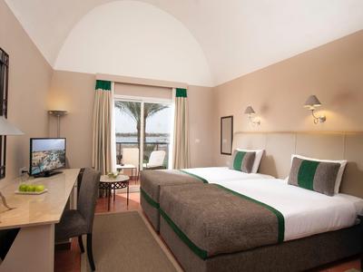 Modern ingerichte hotelkamer met tweepersoonsbed en balkon met zeezicht.