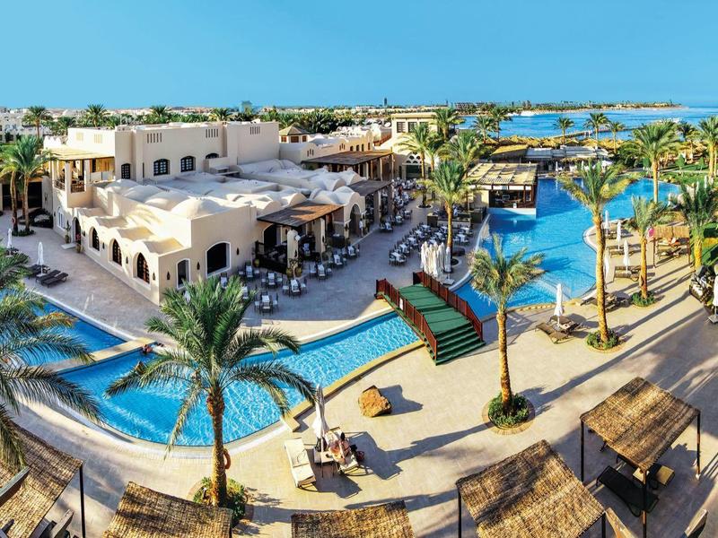 Piscine extérieure avec palmiers, terrasses et vues sur la mer dans un hôtel de luxe.