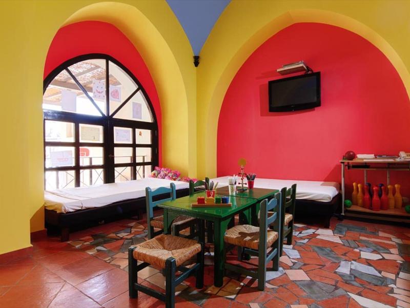 Sala de estar acogedora con paredes coloridas, camas y una mesa pequeña con sillas.