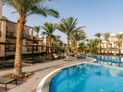 Piscine d'hôtel avec palmiers et chaises longues sous un ciel clair
