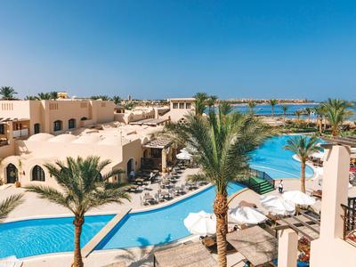 Hotelresort mit Pool, Palmen und weißen Gebäuden unter klarem blauem Himmel