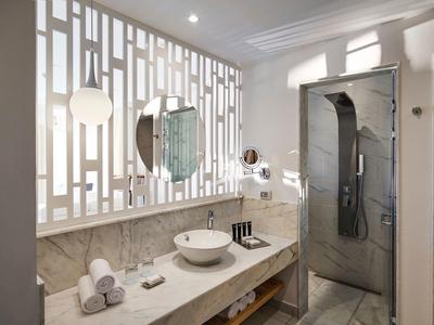 Bagno moderno con lavabo, grande specchio e cabina doccia in un design luminoso.