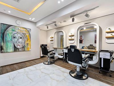 Moderner Friseursalon mit zwei Stühlen, großen Spiegeln und einem Kunstwerk an der Wand.