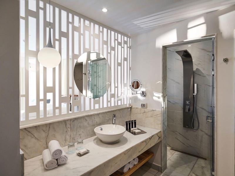 Modernes Badezimmer mit Waschbecken, großem Spiegel und Duschkabine in hellem Design.