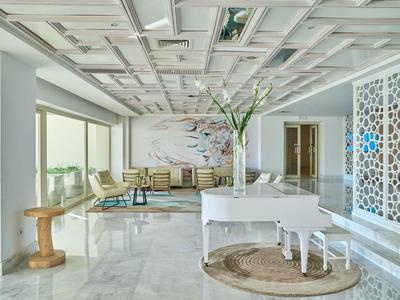 Área luminosa del vestíbulo del hotel con piano blanco y muebles modernos.