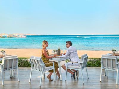 Coppia seduta in ristorante sulla spiaggia che gode di bevande con vista mare.