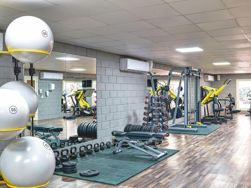 A well-equipped gym with dumbbells, benches, and exercise machines in a modern hotel.