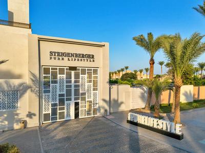 Bâtiment d'hôtel moderne avec des palmiers tropicaux et un ciel dégagé en arrière-plan.