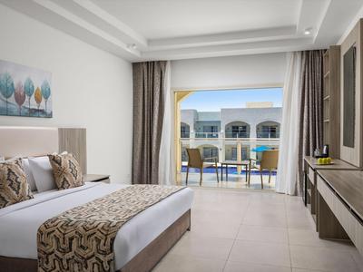 Bright hotel room with double bed and balcony overlooking the outdoor area.