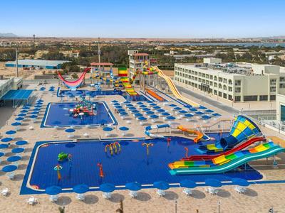 Large waterpark resort with multiple pools, water slides, and sun umbrellas in a sunny landscape.