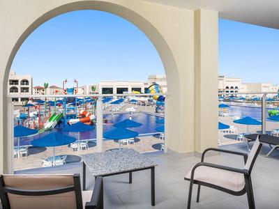 Balkon mit Blick auf Pool und Sonnenschirme in einem Hotelresort.