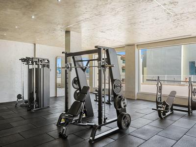 Moderne sportschool met krachtstation en fitnessapparatuur in een lichte, ruime kamer.
