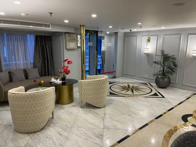 Moderne woonkamer met comfortabele fauteuils, bank en decoratief tapijt op marmeren vloer.