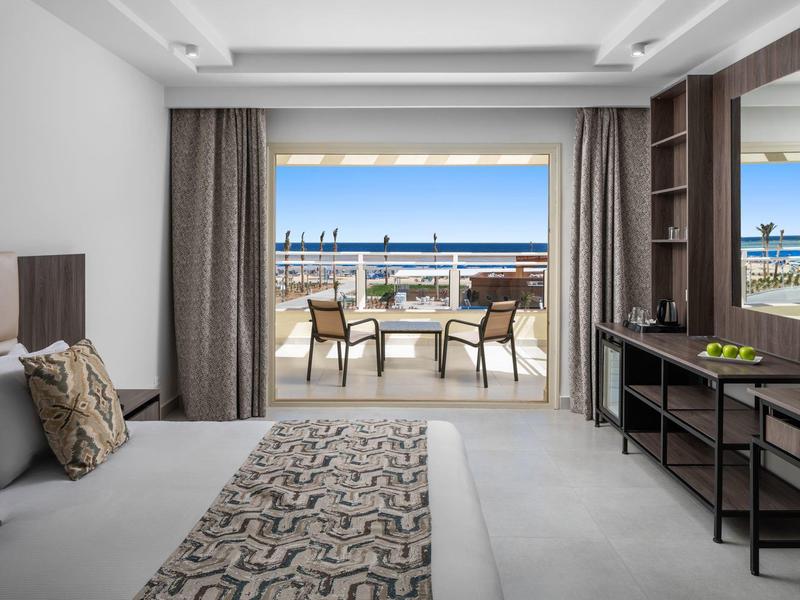 Modernes Hotelzimmer mit Balkon und Meerblick, ausgestattet mit Bett, Stühlen und Schreibtisch.