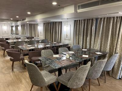 Modern dining area with multiple tables and upholstered chairs in a warm setting.