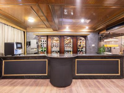 Bar d'hôtel élégante avec plafond en bois, comptoir noir et bouteilles en arrière-plan.
