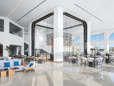 Hall d'hôtel moderne et lumineuse avec des espaces assis et de grandes fenêtres donnant sur la mer.